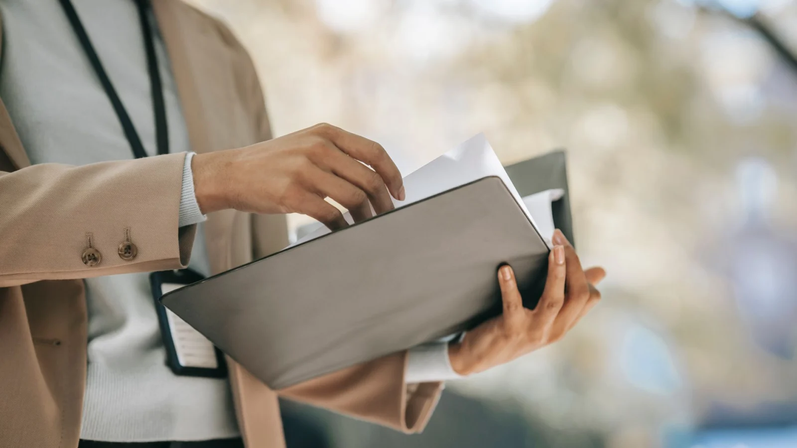 Crop anonymous female entrepreneur in elegant jacket with badge looking through papers in folder